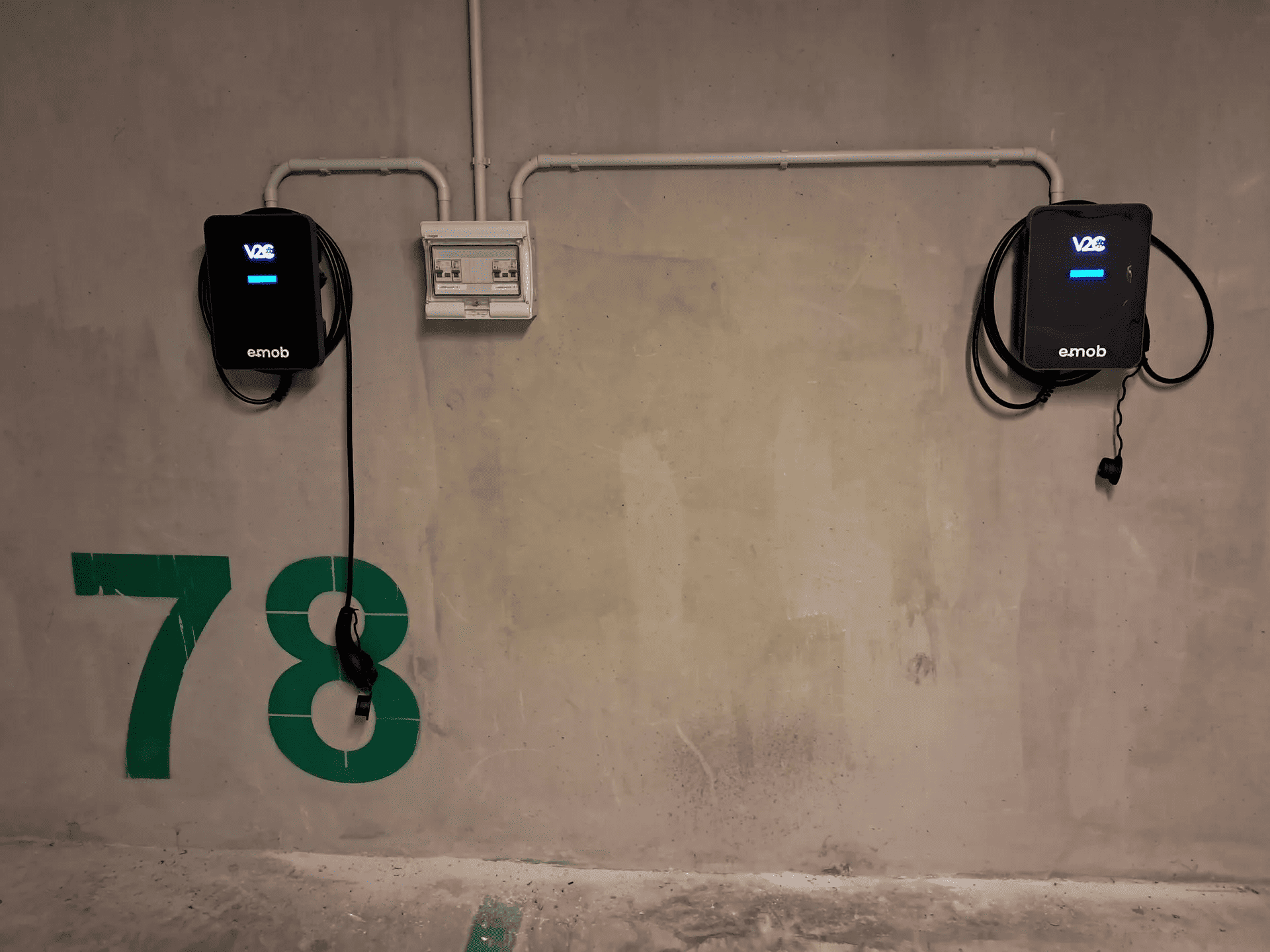 Dois carregadores de carros elétricos montados na parede da garagem de um condomínio