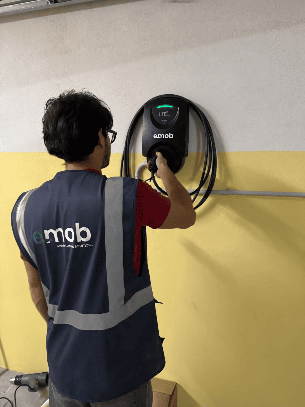 Técnico a ligar um carregador de carros elétrico num condomínio