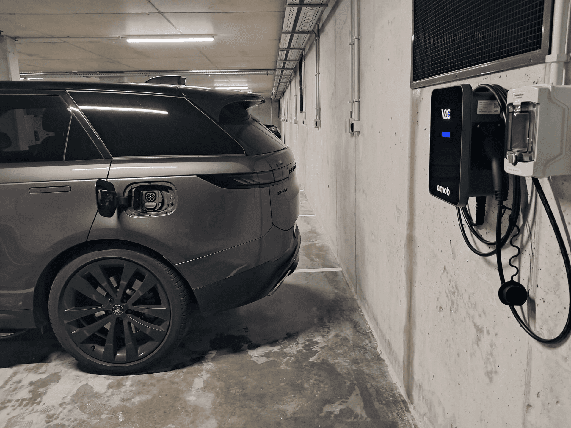 Carro elétrico estacionado numa garagem de um condomínio, à beira de um carregador da e-mob