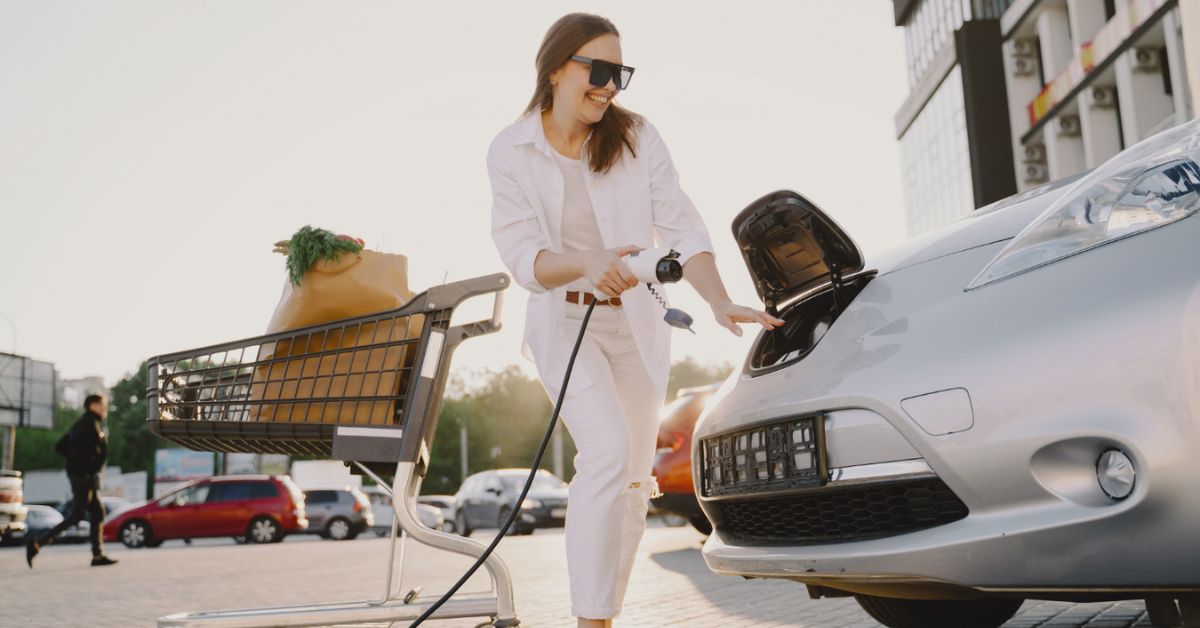 Mulher a carregar um carro elétrico num supermercado. 